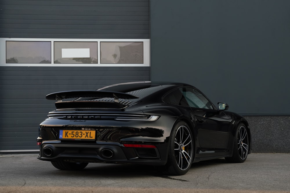 a black porsche sports car parked in front of a garage