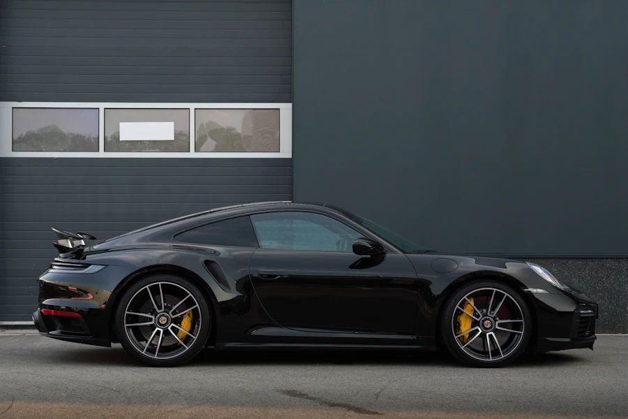 Black Porsche 911 Turbo S side view against a dark wall