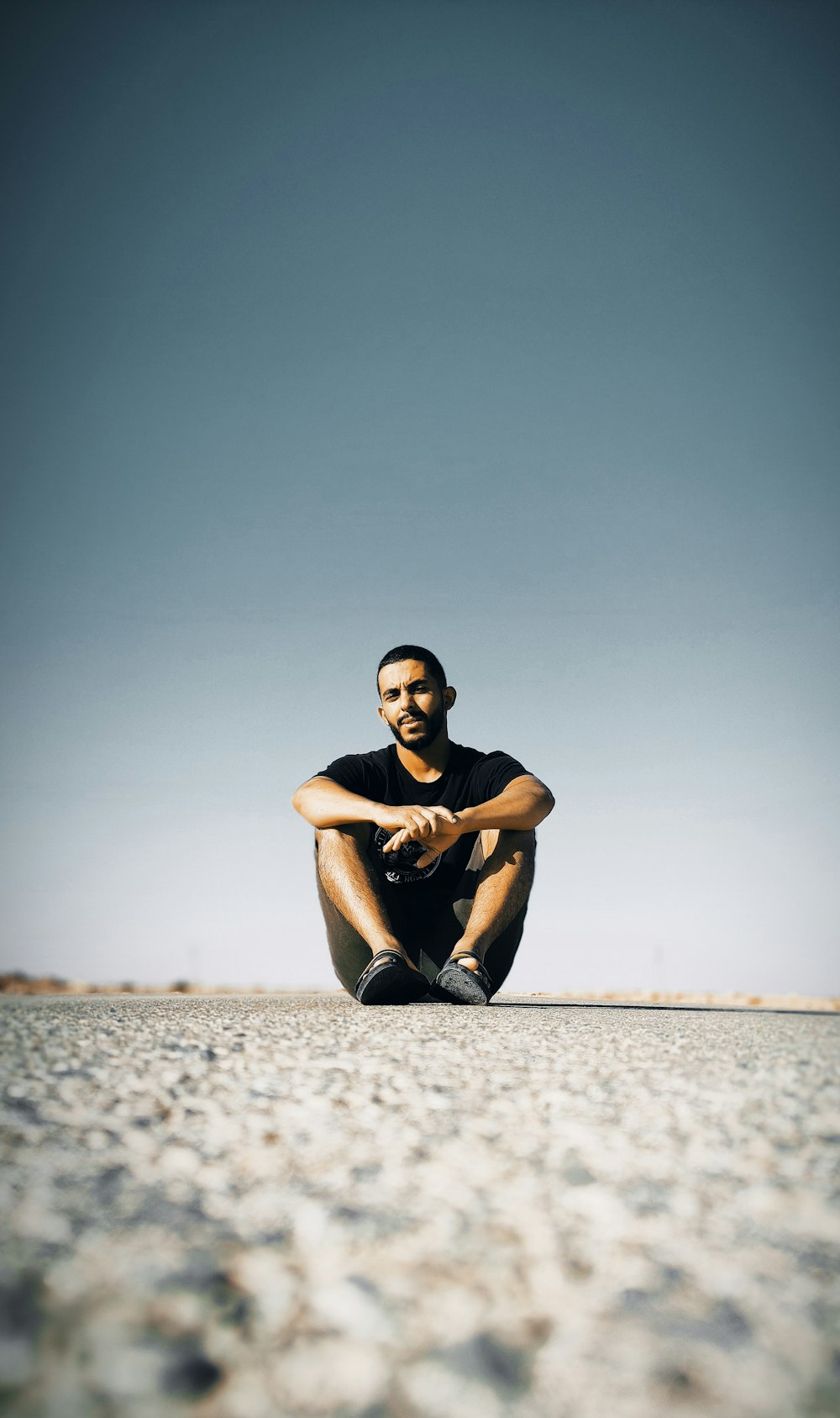 a man sitting on the ground in the middle of nowhere