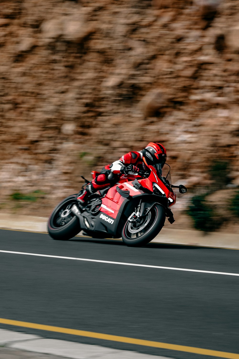 a man riding a red motorcycle down a curvy road