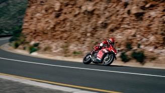 a man riding a red motorcycle down a curvy road