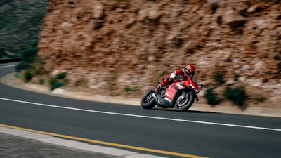 a man riding a red motorcycle down a curvy road