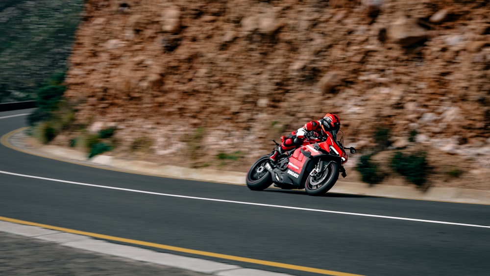 Un hombre conduciendo una motocicleta roja por una carretera con curvas