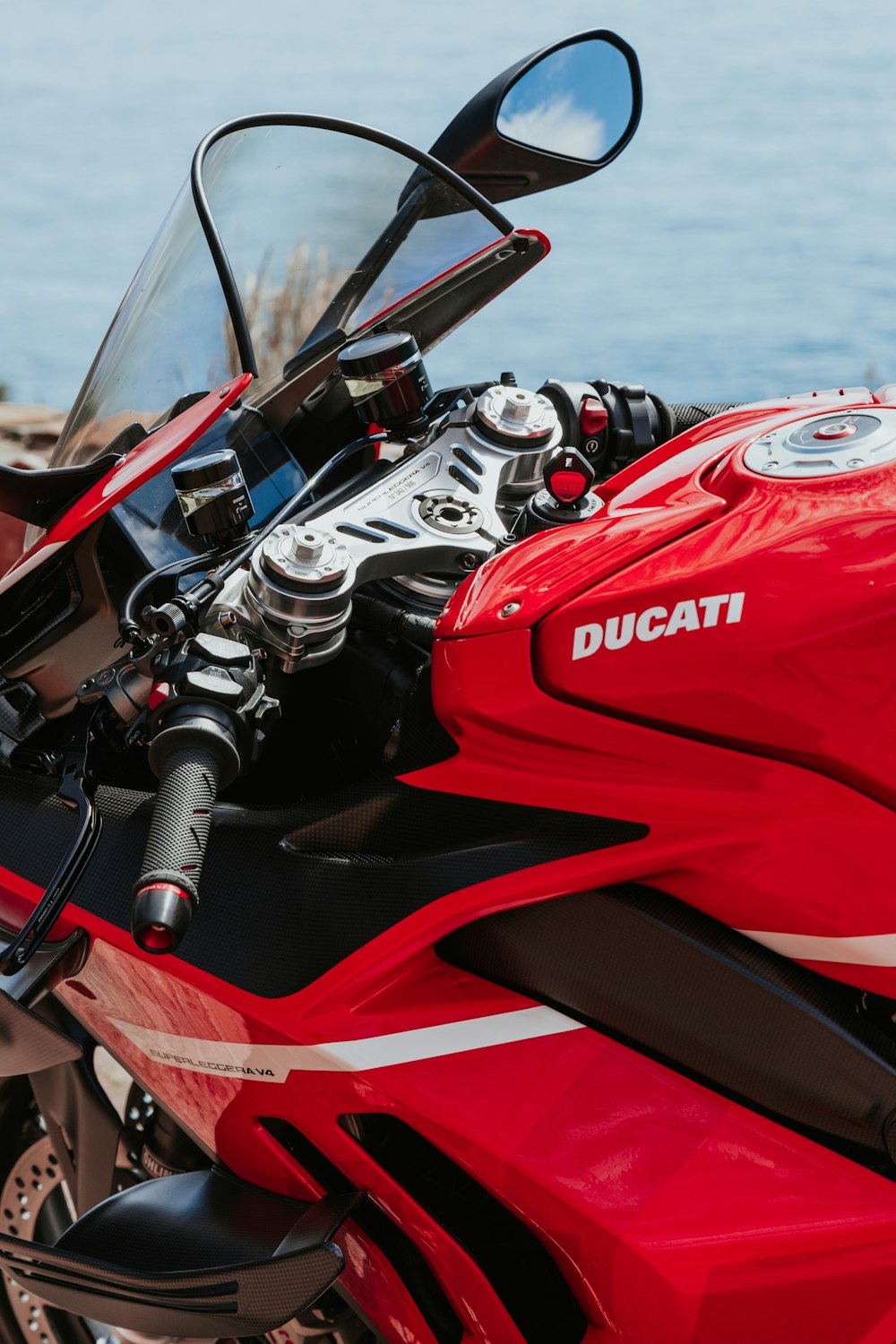 a red motorcycle parked next to a body of water