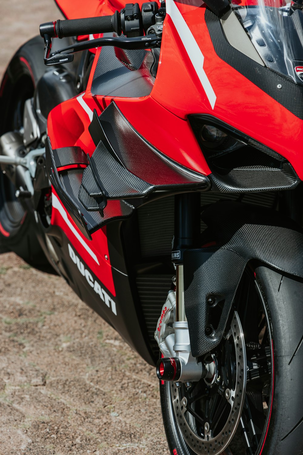 Ein rot-schwarzes Motorrad, das auf einem Feldweg geparkt ist