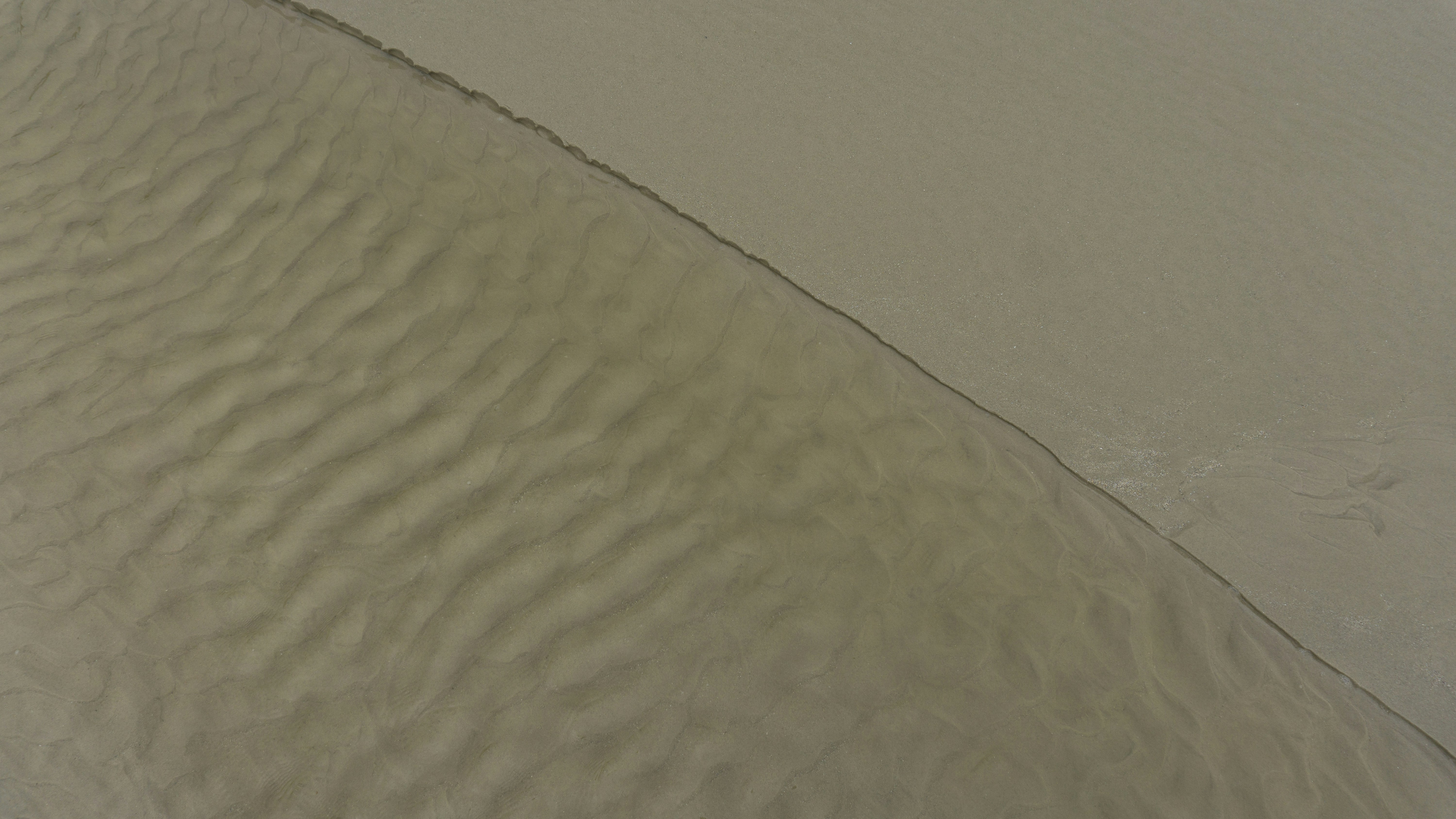 a person riding a surfboard on top of a sandy beach