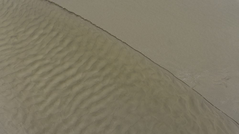 a person riding a surfboard on top of a sandy beach