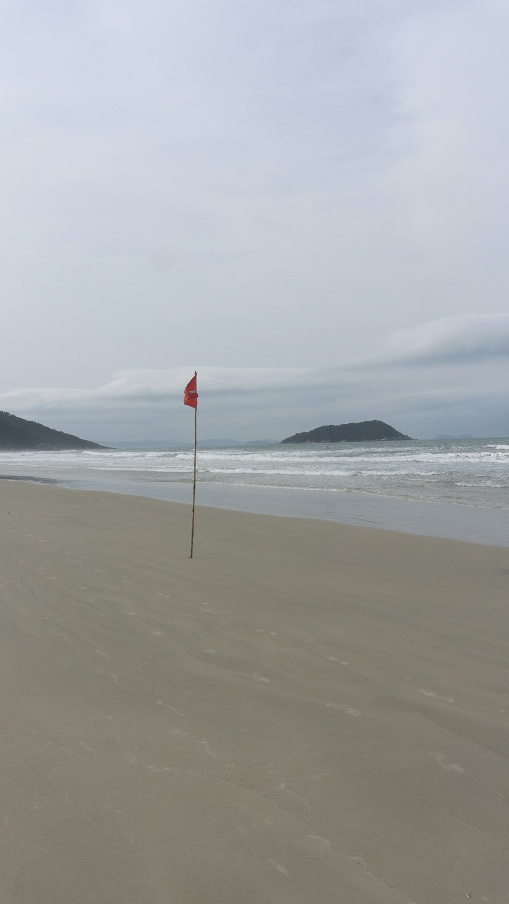a red flag is sticking out of the sand at the beach