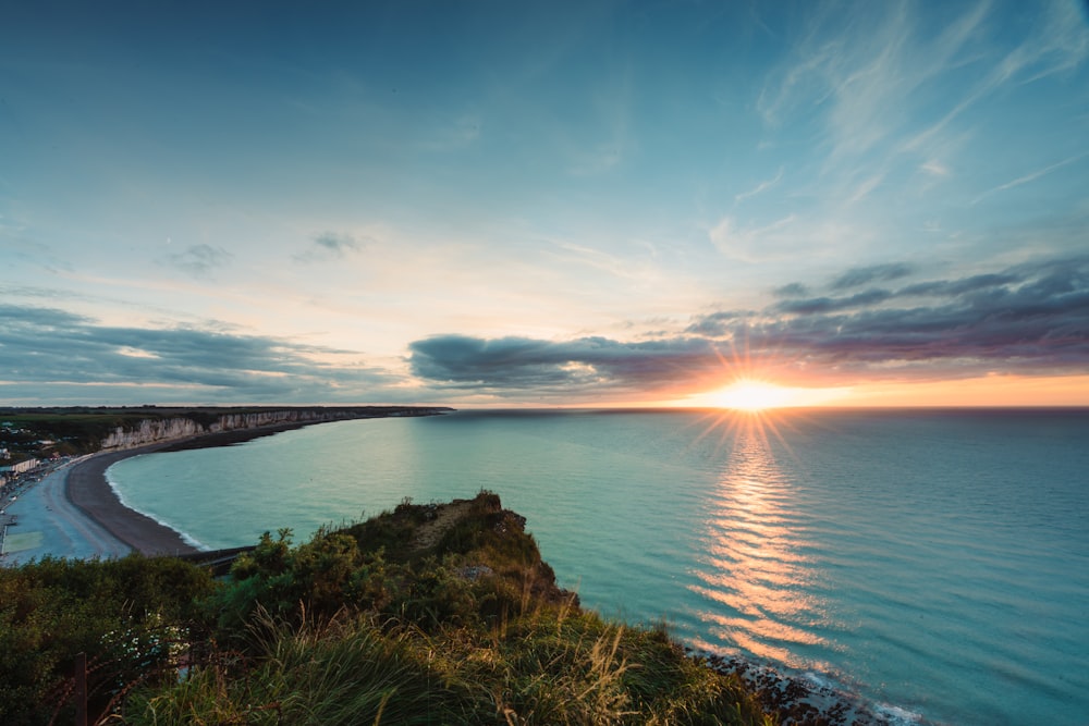 the sun is setting over the ocean on a cloudy day