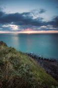 A stunning view of a coastal property with a sunset in the background.