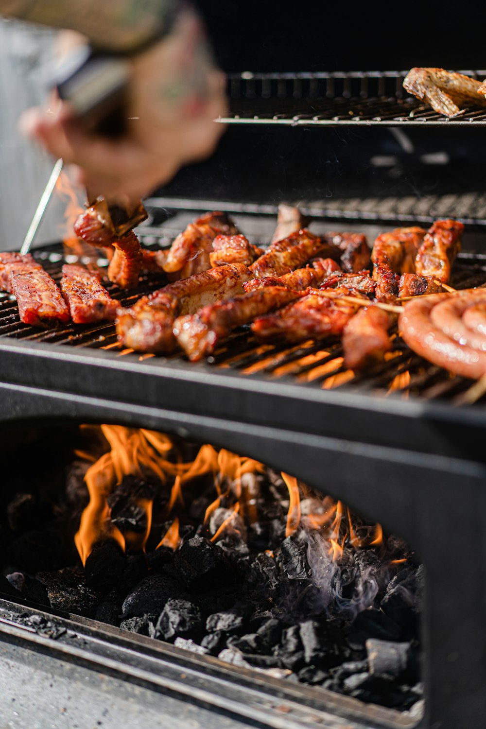 a person grilling hot dogs and sausages on a grill