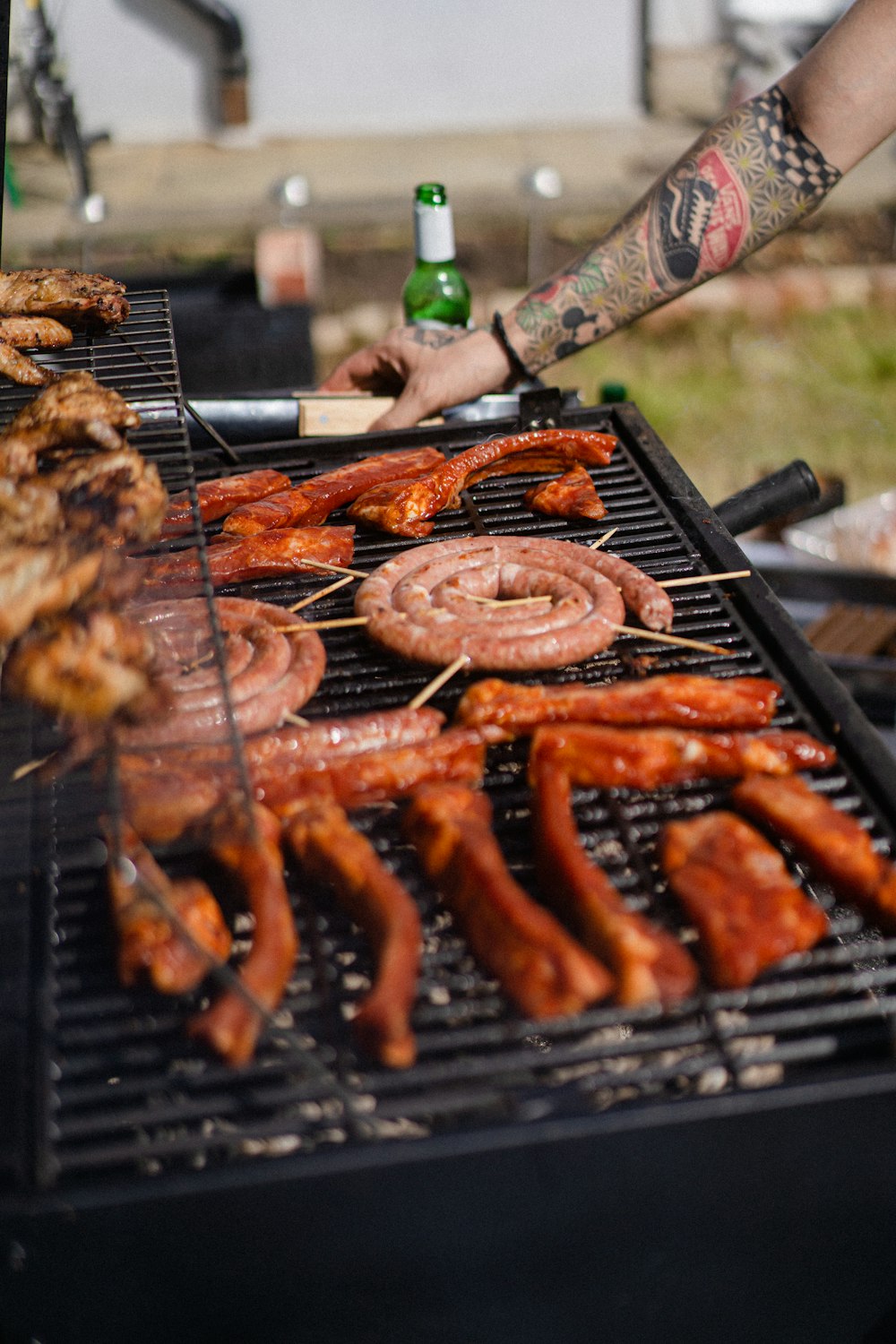 a man cooking hot dogs and sausages on a grill