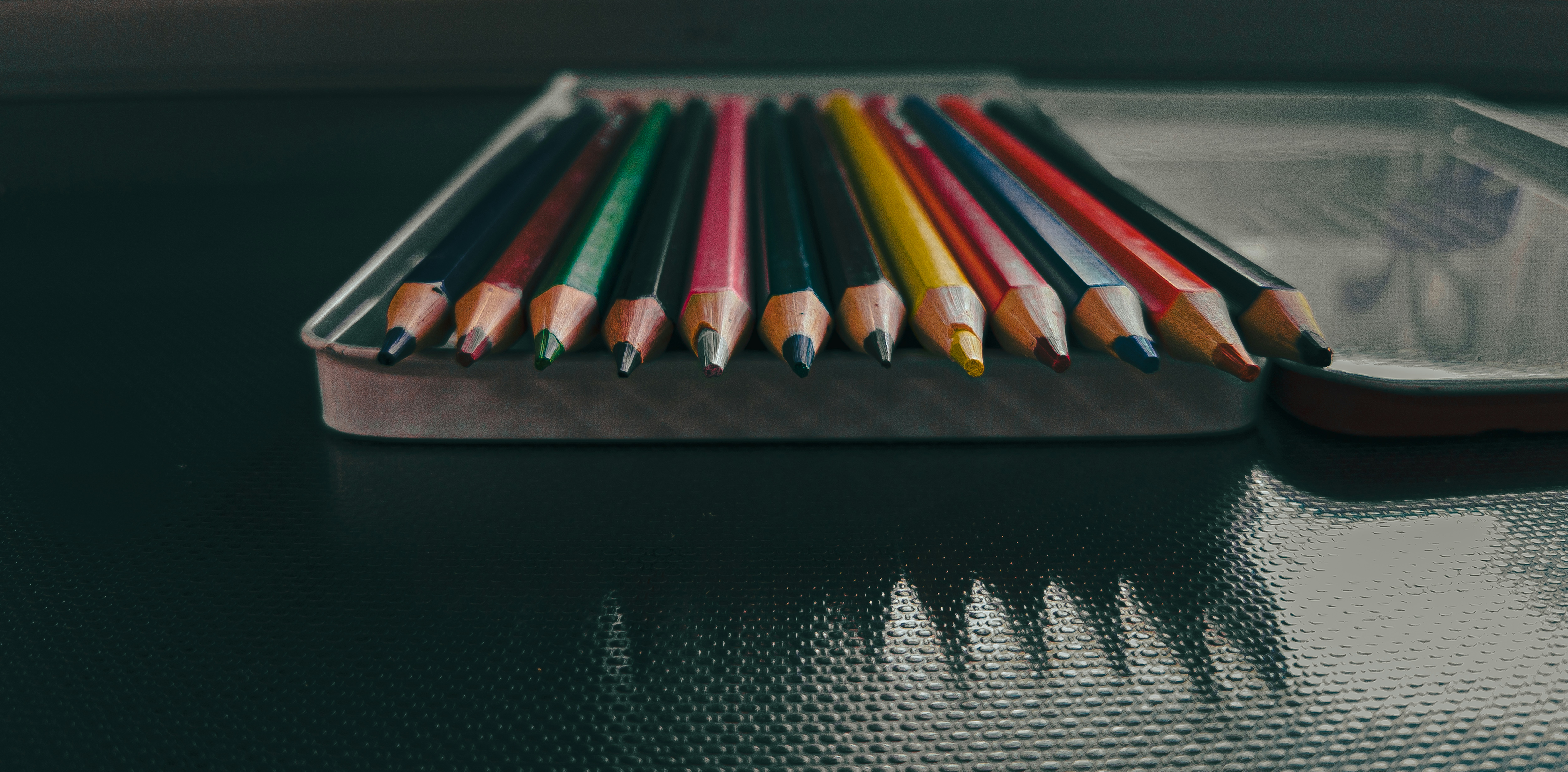 a row of colored pencils sitting on top of a table