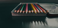 a row of colored pencils sitting on top of a table