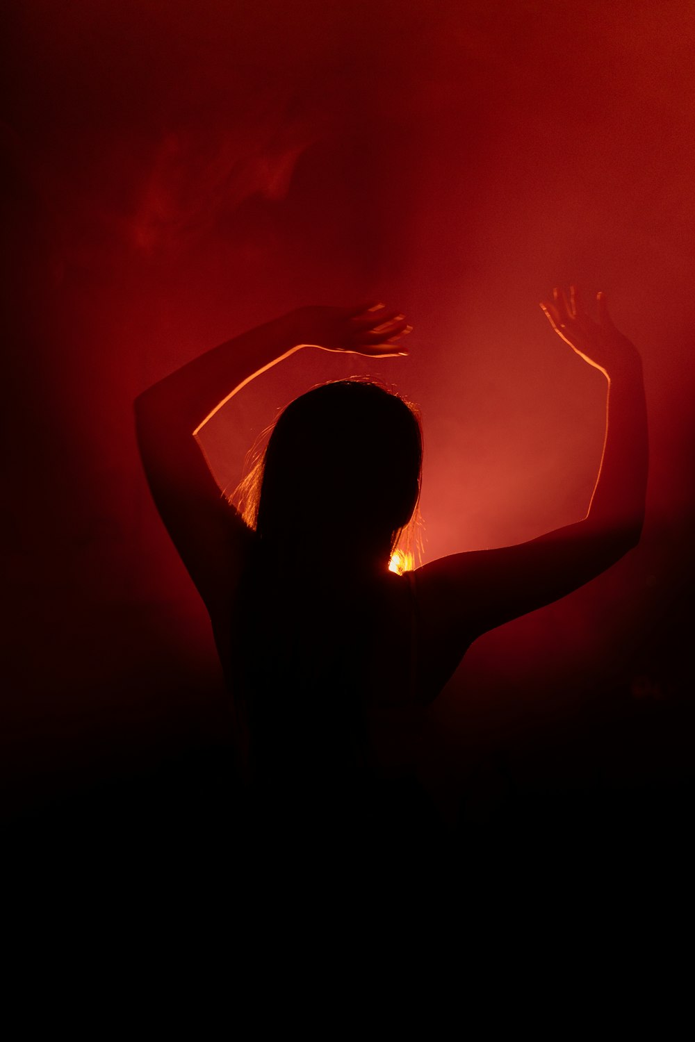 a woman dancing in the dark with her arms raised