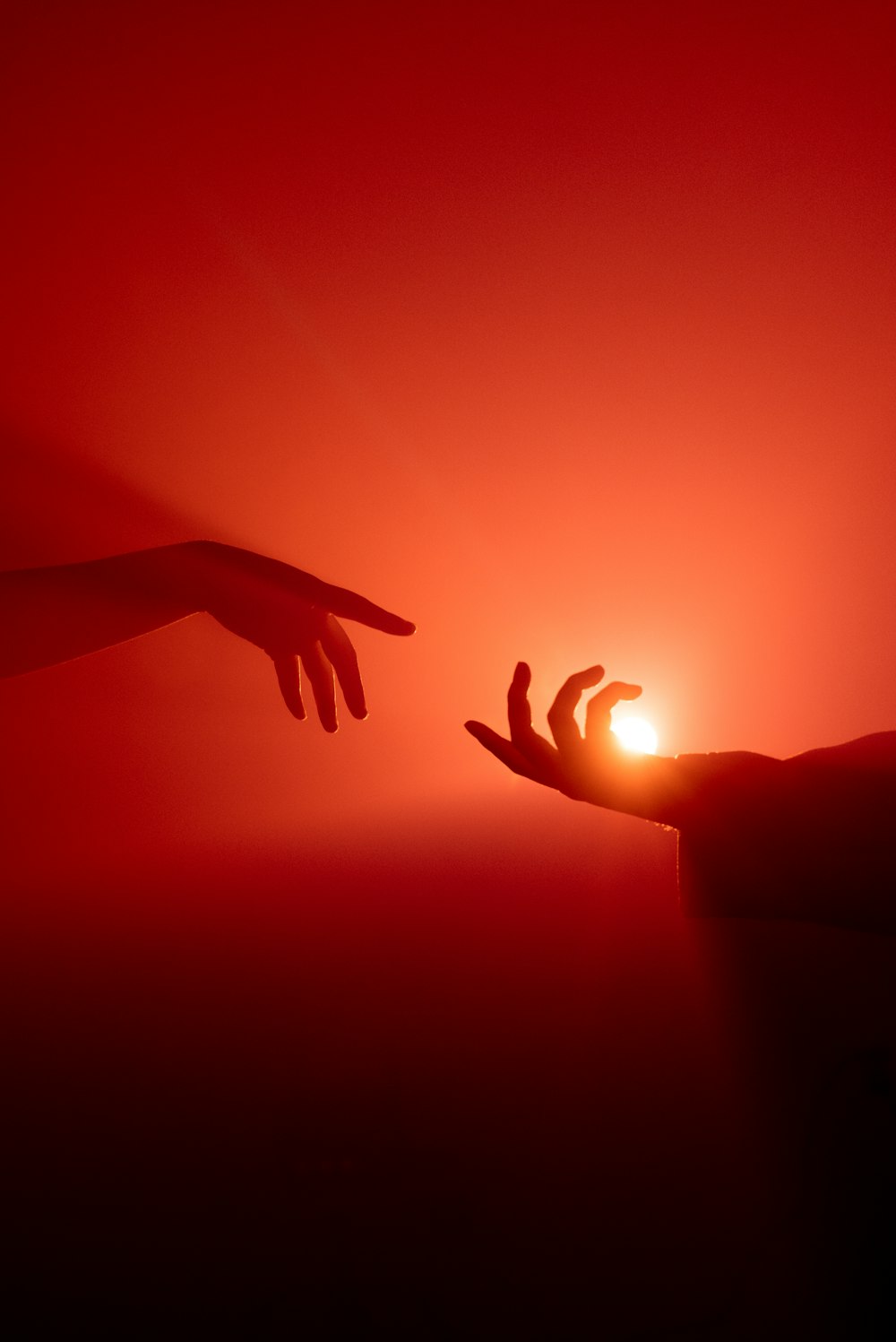 duas mãos se aproximando uma da outra com o sol ao fundo