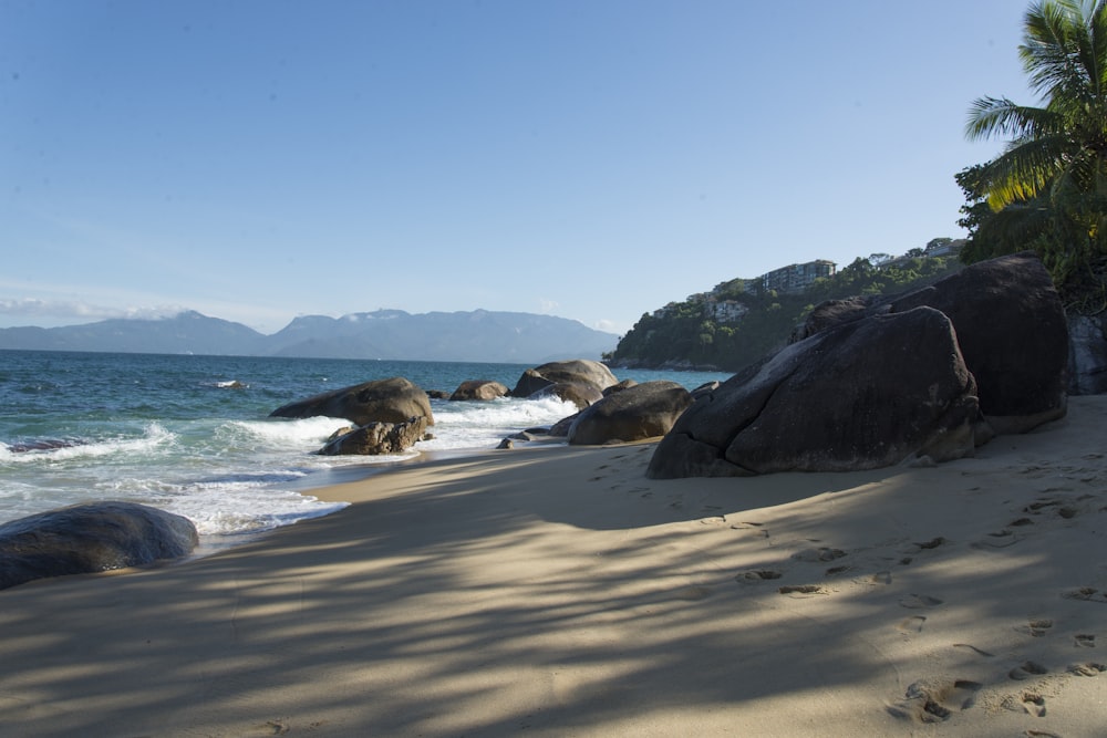 a sandy beach with large rocks and water