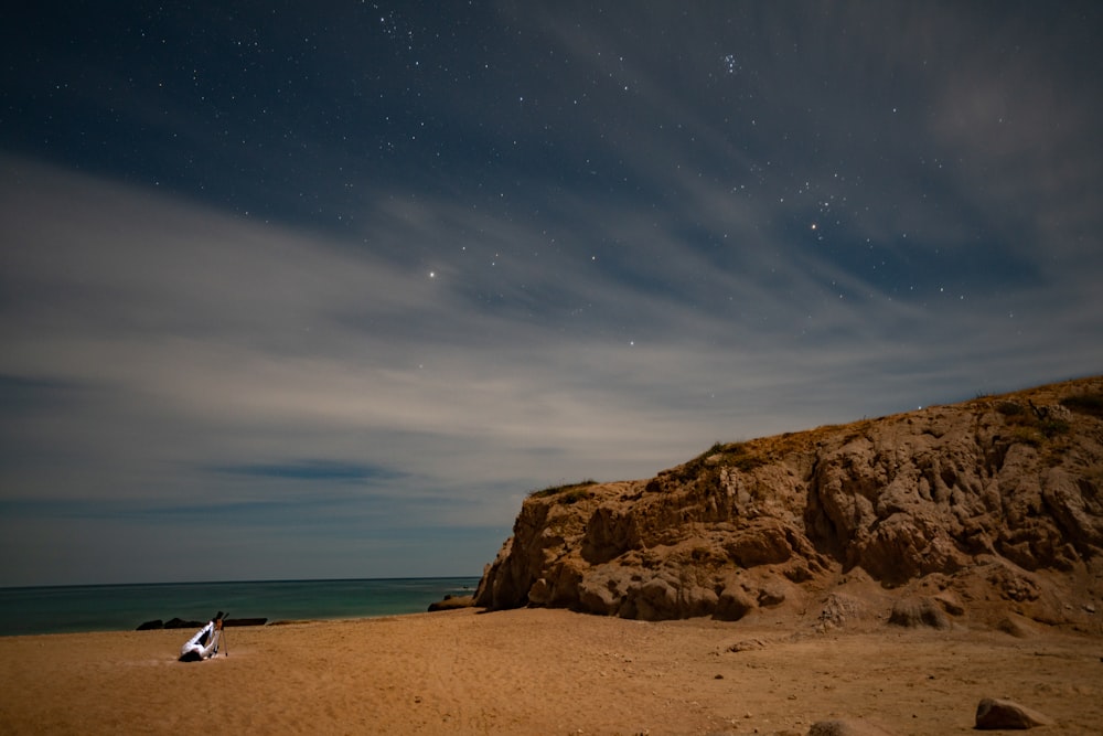 a person sitting on a beach under a night sky