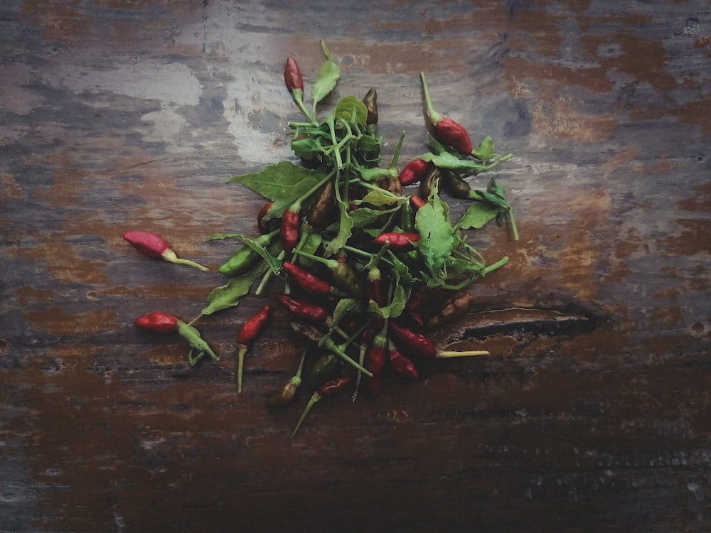 a pile of green and red peppers on a wooden table