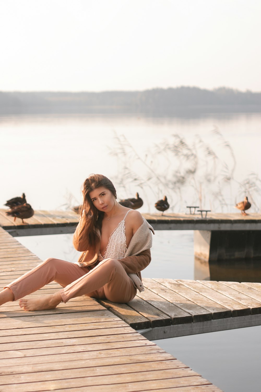 a woman sitting on a dock next to a body of water