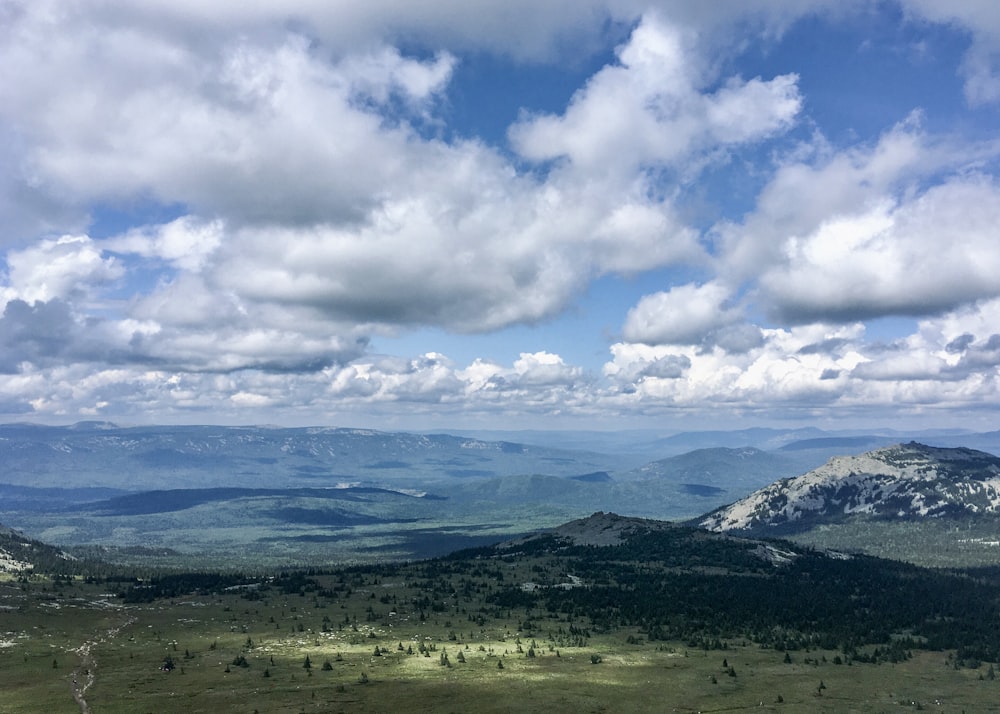 a scenic view of a valley with mountains in the background