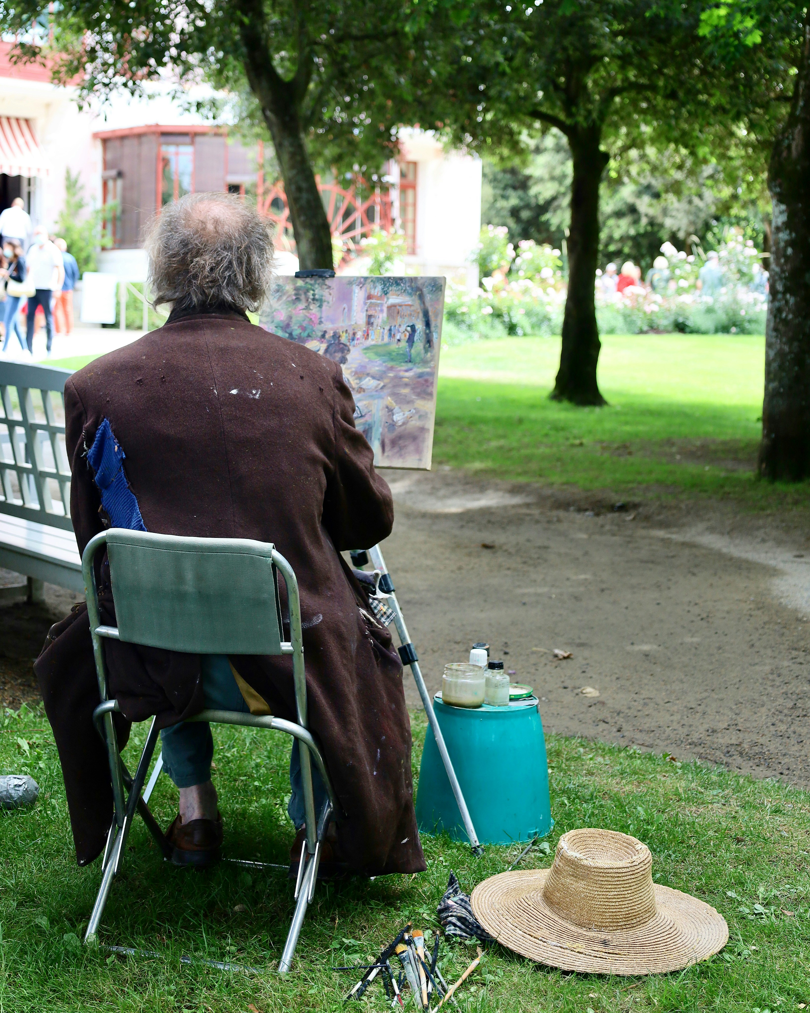 a man sitting in a chair painting on a park bench