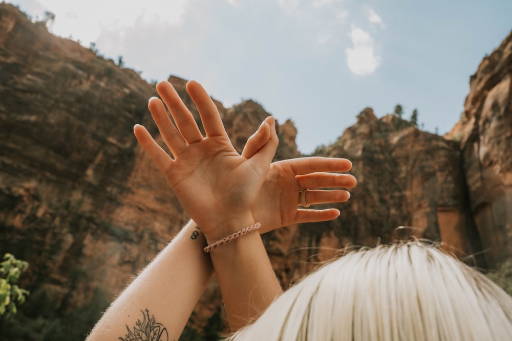 a close up of a person's hands with a mountain in the background