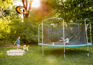 two children playing on a trampoline in a yard