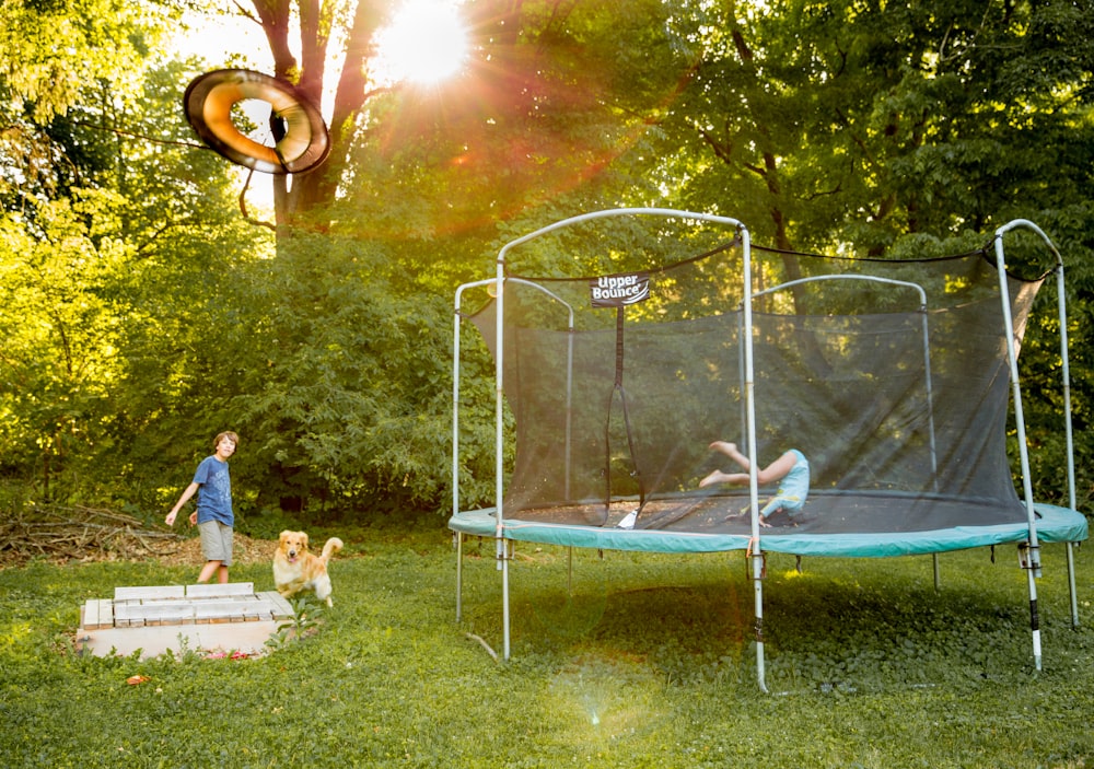 two children playing on a trampoline in a yard