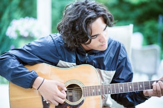 a man playing a guitar outside in the sun
