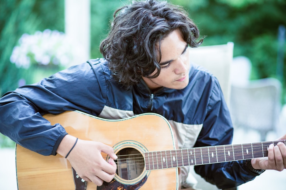 a man playing a guitar outside in the sun