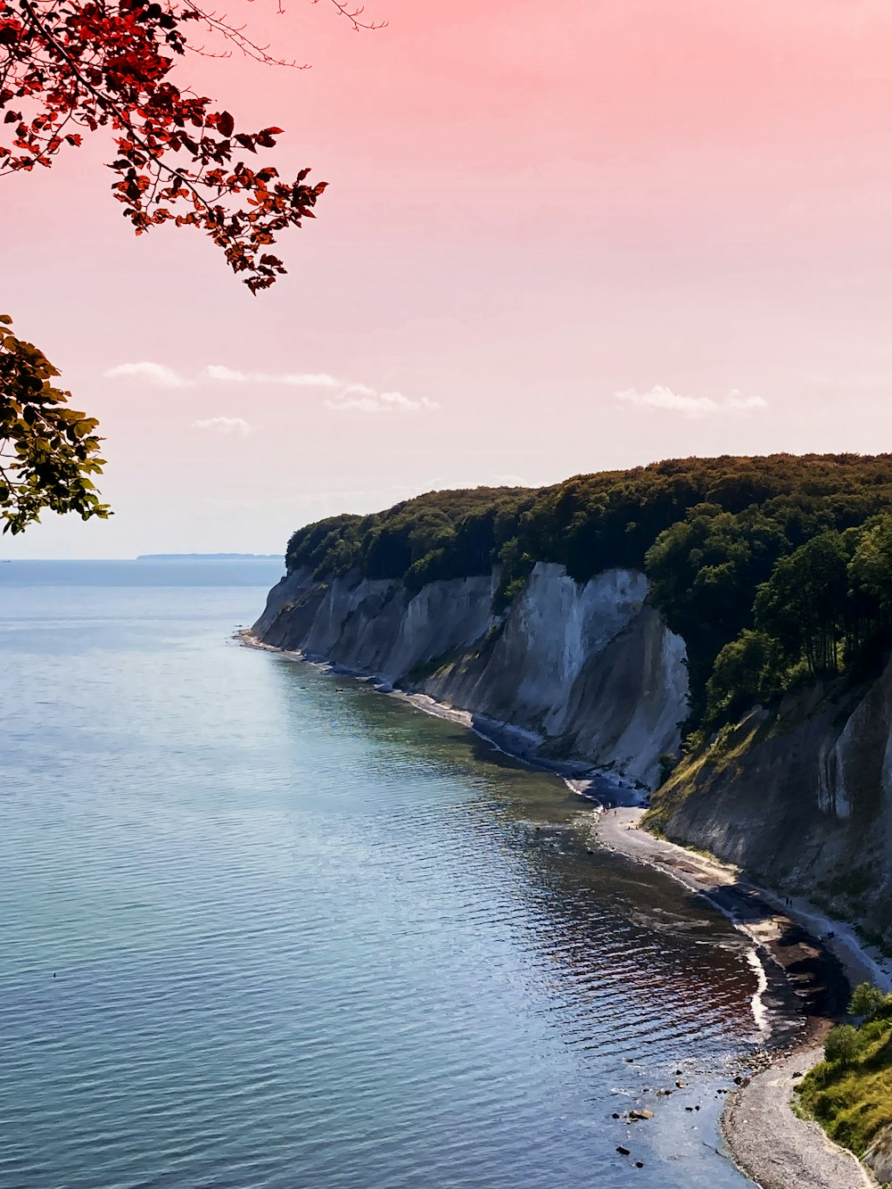 a large body of water next to a lush green hillside