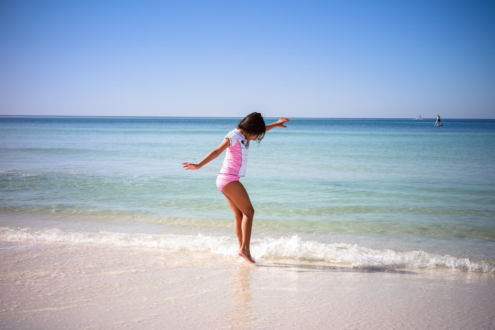 a woman in a pink bathing suit standing on a beach