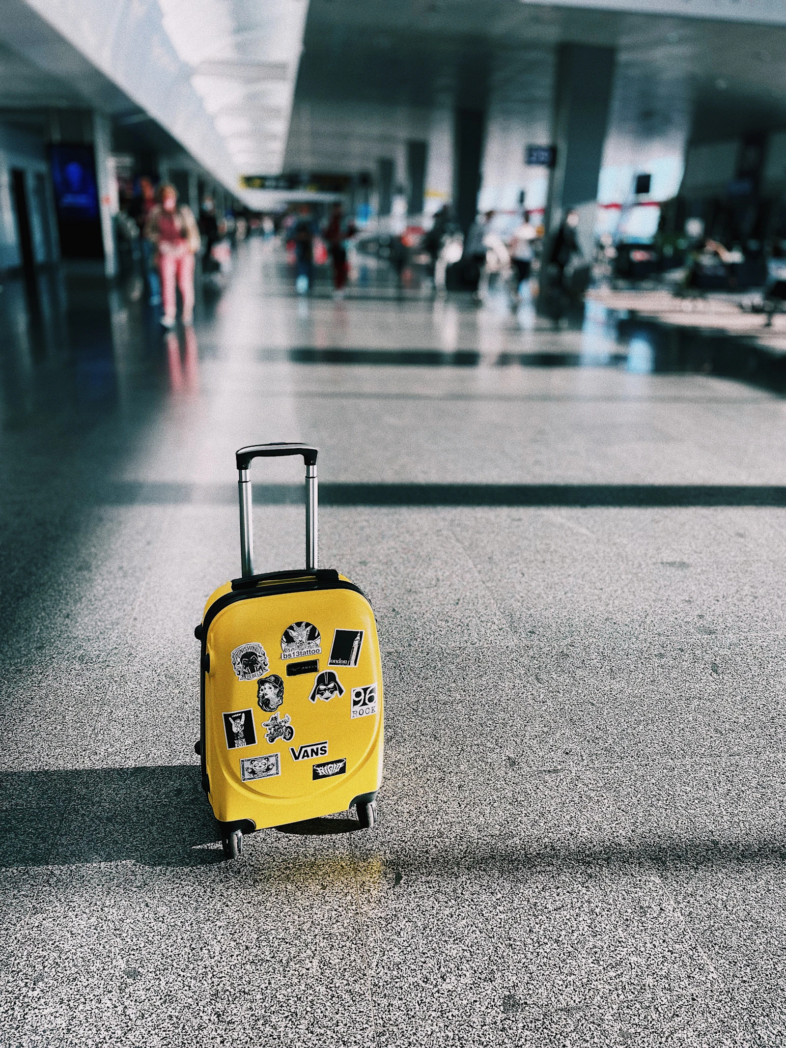 A yellow suitcase standing on its own on a floor