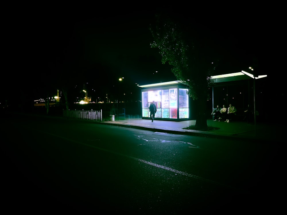 a bus stop sitting on the side of a road at night