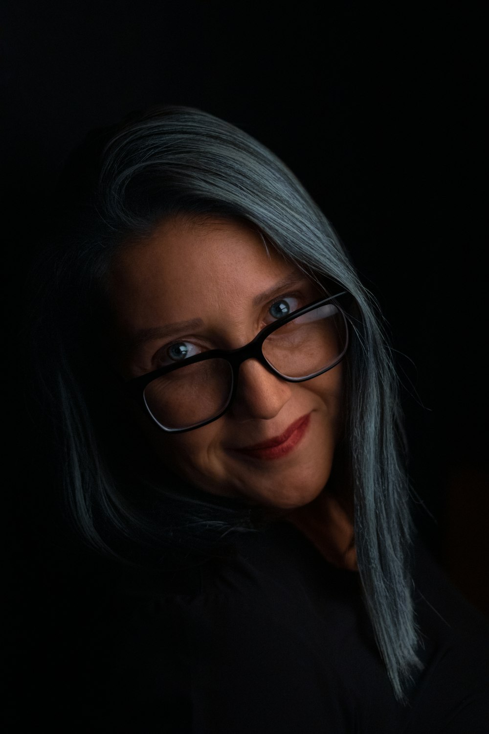 a woman with grey hair and glasses posing for a picture