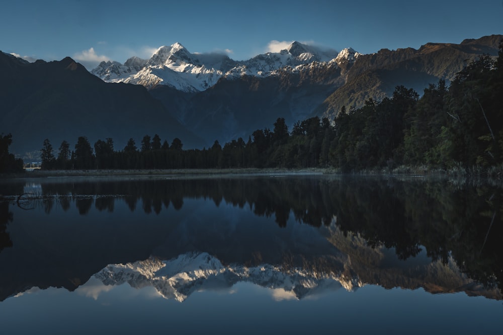 a mountain range is reflected in the still water of a lake