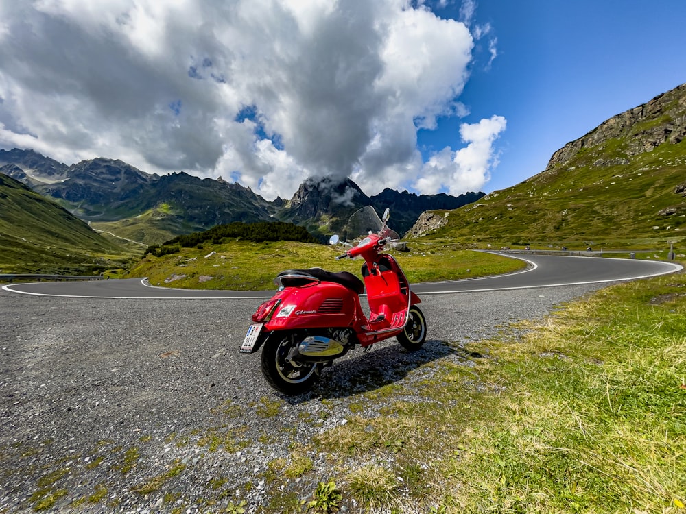 a red scooter parked on the side of a road