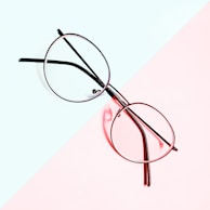 Elegant round glasses with thin metal rims showcased against a soft blue background.