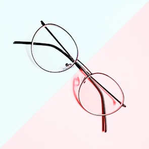 A stylish pair of optical frames displayed against a soft pastel background.