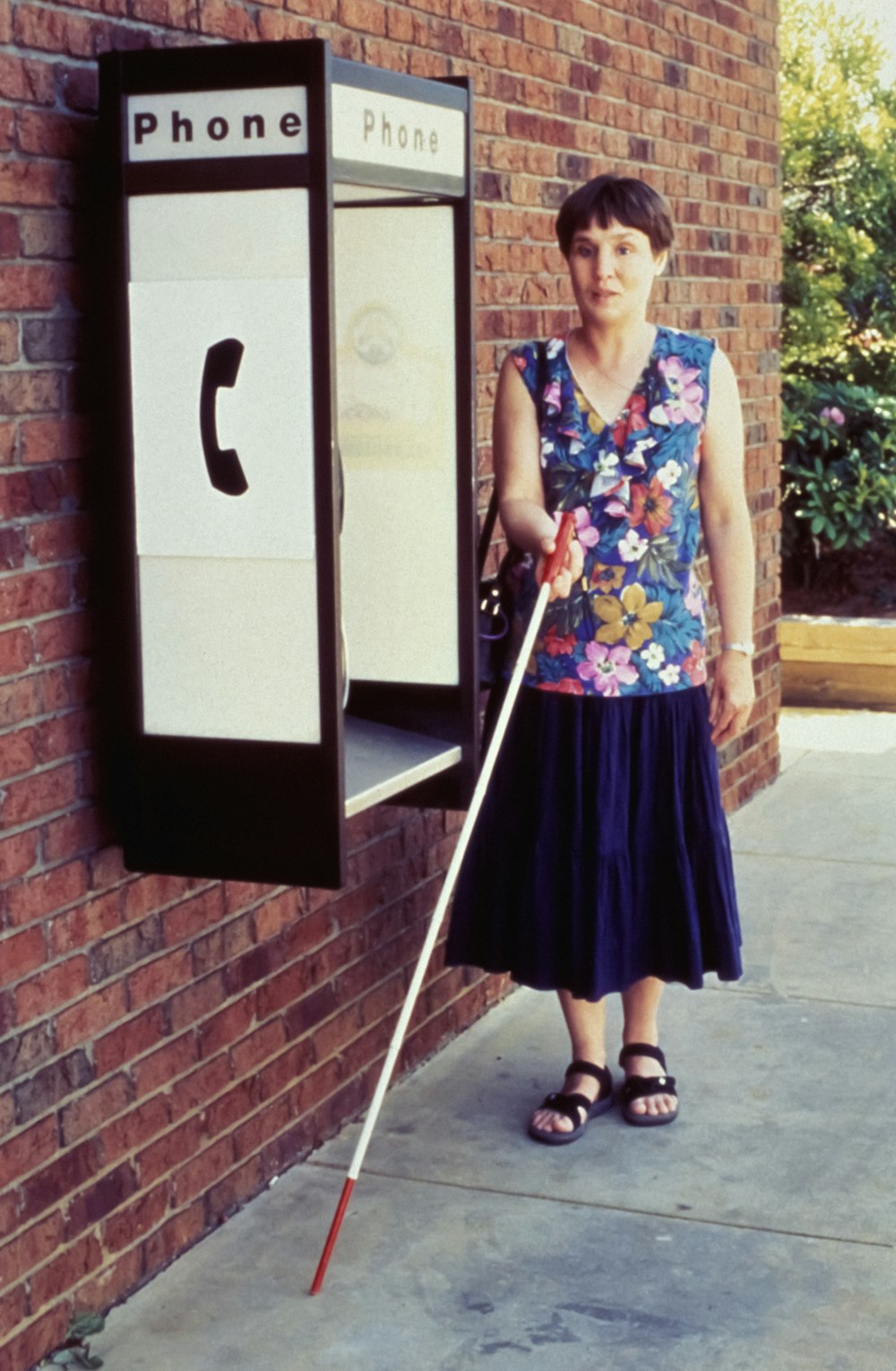 uma mulher em pé ao lado de uma cabine telefônica