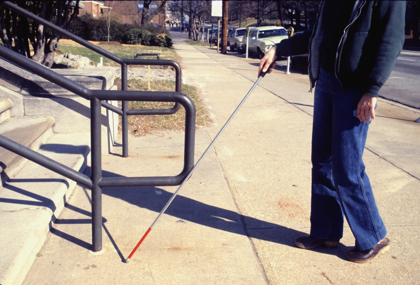 A person walking a dog on a leash along a city sidewalk