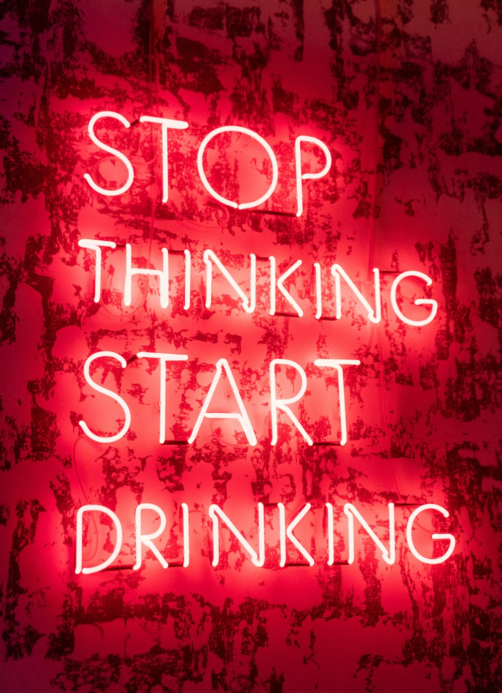 a neon sign that says stop thinking start drinking