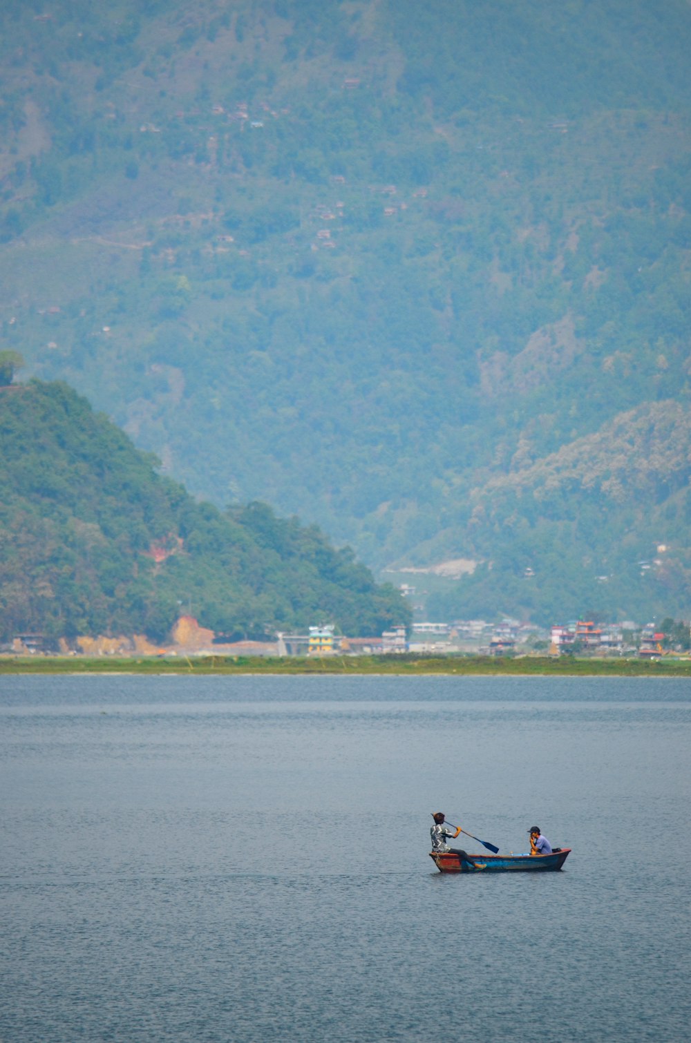 two people on a boat in the middle of a lake