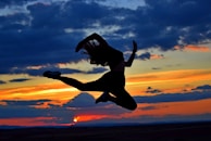 a woman jumping in the air at sunset