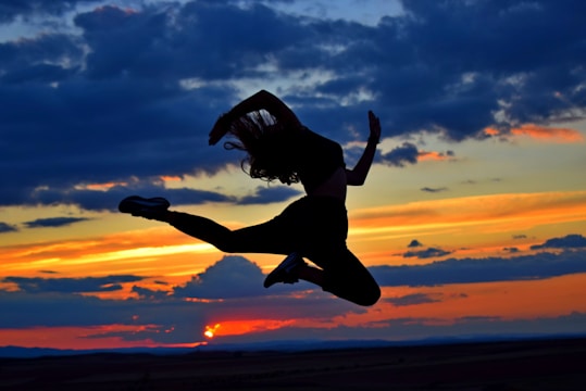 a woman jumping in the air at sunset