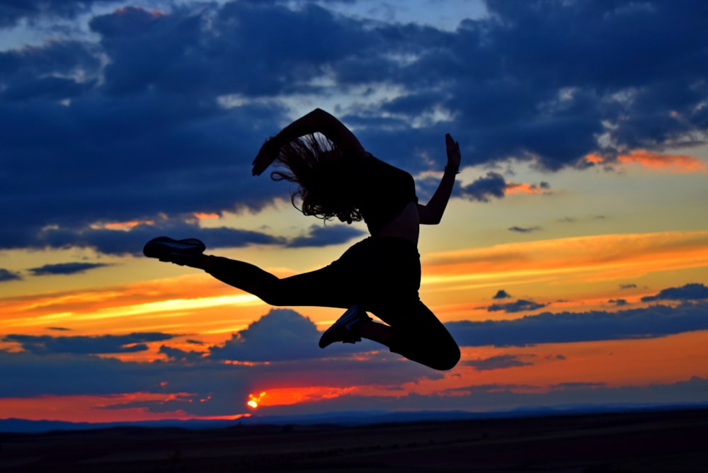 Una donna che salta in aria al tramonto