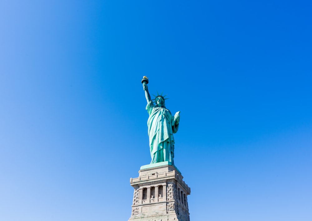 the statue of liberty stands tall against a blue sky