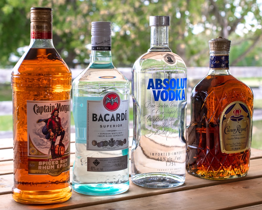 three bottles of alcohol sitting on top of a wooden table