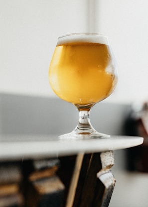 a glass of beer sitting on top of a table